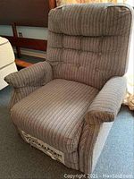 Front view of the blue vertically striped upholstered Stratolounger recliner chair showing cushioned armrests and padded backrest with button tufting.
