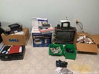 Overall view of all electronics and boxes, including printers, TVs, routers, cords, power strips in boxes and bins