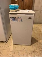 Full view of Avanti compact refrigerator showing white single-door design with wear marks and label.