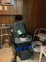 Quantum Rehab electronic wheelchair and walker with shower seat and elevated toilet seats in background