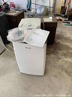 White Hisense dehumidifier with user manual and plastic tubing on top, showing front and top features.