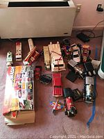 Photo showing all toy vehicles and playsets spread on carpet, including boxes and various vehicles.