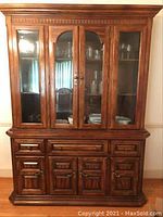 Full view of closed wood china cabinet with glass doors and multiple drawers and cabinets below.