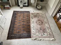 Two area rugs laid out on carpeted floor showing full patterns and condition.