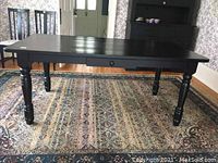 Three-quarter view of rectangular dining table showing turned legs and drawer