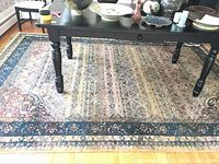 Full view of the rug under a black table showing the overall design and colors.