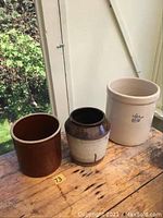 Three earthenware pots on wooden surface, showing size and color variety