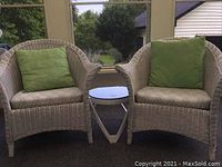 Front view of two white wicker chairs flanking a small round table