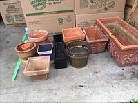 All pots and flower boxes together on concrete floor against cardboard boxes background