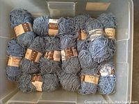 Blue/grey yarn skeins in plastic bin showing about 15 skeins.