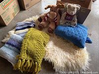 Photo showing the sheepskin throw on the bottom with multiple knitted blankets and two stuffed animals arranged on top