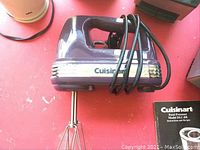 Vintage Cuisinart dark blue hand mixer with power cord wrapped around handle, visible beaters attached