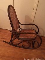 Side view of the bentwood rocking chair showing curved armrest and rocker profile with cane seat and backrest.
