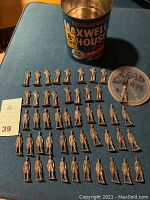 Top-down view of 40 lead toy soldiers and a vintage Maxwell House coffee can on a blue surface, soldiers spread in rows with a plastic lid labeled 'LEAD Soldiers'.