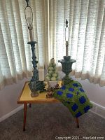 Full group shot showing two lamps on wooden table with yellow top, crocheted afghan draped over table, bowl with artificial lemons, and two small hurricane lamps