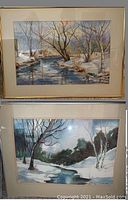 Two framed watercolor paintings shown together, winter landscapes with snow and trees by streams