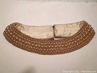 Top view of pearl collar necklace showing multiple rows of pearls on cream fabric backing.