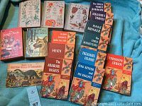 Photo showing a selection of vintage classic children's books including The Jungle Book, The Call of the Wild, and others on a blue fabric background.