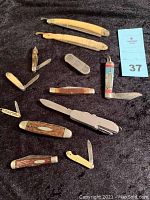 Group photo showing all vintage pocket cutters and straight razors laid out on black fabric.