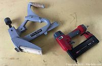 Both nailers on a table, showing Porta-Nailer on the left and red Senco FinishPro 18 nail gun on the right