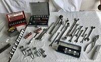 Full view of assorted crescent, ratchet wrenches, and socket sets spread on a table with several socket bits and extensions visible.