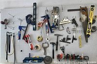 Full view of pegboard with assorted tools including saws, clamps, levels, scissors, speed squares, hammers and caulking gun.