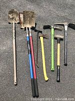 Full view of all tools showing 3 shovels, 2 mattocks, axe, sledgehammer, and wrecking bar