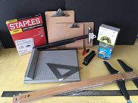 Sheet protectors, paper cutter, T-squares, clipboards, stapler, tape dispenser, and pencil sharpener in a group photo