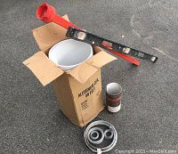 Photo of aluminum coil box labeled 'Aluminum Coil 50 Feet' containing coiled aluminum, black rectangular Swanson level with red carrying case, baling wire coils, and cylindrical metal container.