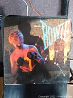 Front cover of David Bowie's Let's Dance vinyl album from 1983 showing the artist in boxing gloves with black and orange design.