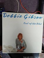 Front cover of Debbie Gibson's "Out of the Blue" vinyl album showing artist seated next to a white teddy bear against a plain background