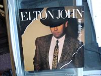 Front cover of 1981 Elton John Breaking Hearts vinyl album showing some wear and large tear on cover.