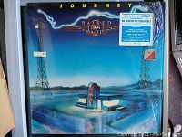 Photo of the front album cover of 'Raised on Radio' by Journey, showing artwork and inclusion sticker.