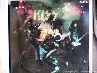 Front cover of the Kiss Alive album showing band members on stage with instrument and smoke effects