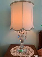 Pair of glass lamps each on lace doily mat, lit, showing full view