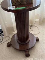 Front view of the solid wood pedestal side table showing round top and fluted central column