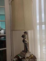 Full view of tall lamp showing shade, stem and base on small round table