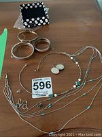 Full view of all jewelry items on wooden table with black and white polka dot box included