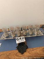 Top-down view of six frosted glass liqueur glasses with sterling silver holders arranged on the sterling silver serving tray.