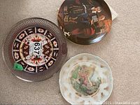 Top view of the three plates showing their different artistic styles and silver trim on the Royal Crown Derby plate