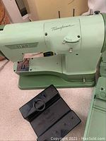 Side view of vintage light green Elna Transforma sewing machine showing convertible base and brand name.