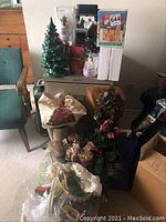 Overall view of vintage ceramic Christmas tree lamp, boxed porcelain houses, Christmas wreath, gift bags, and wrapping paper stacked together