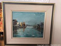 Framed oil painting showing harbor and boats scene with sky and water reflections.
