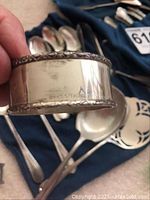 Hand holding a round sterling napkin ring with rope-edge detailing and hallmarks