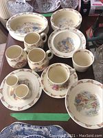 Photo of multiple ceramic Bunnykins cups, saucers, cereal bowls, and dishes showing the Bunnykins illustrations and signs of wear.
