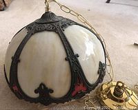 Full view of antique hanging lamp showing stained glass panels with ornate dark brass framing and chain.