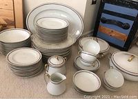 Full set displayed on carpet showing plates, cups, bowls, covered dishes, creamer and sugar bowl