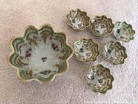 Overall view of the large serving nut bowl and six smaller nut bowls, showing floral designs and scalloped edges