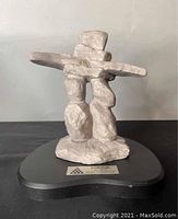 Front view of the Inukshuk sculpture on black base with metal plaque label