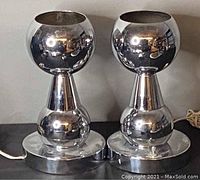 Pair of chrome orb table lamps showing front view and mirrored surfaces reflecting surroundings